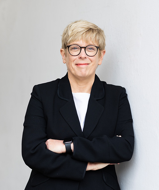 Image of Kristin Heimark leaned against a wall, with arms folded.